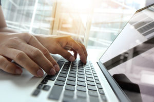 Man Typing on Laptop Computer